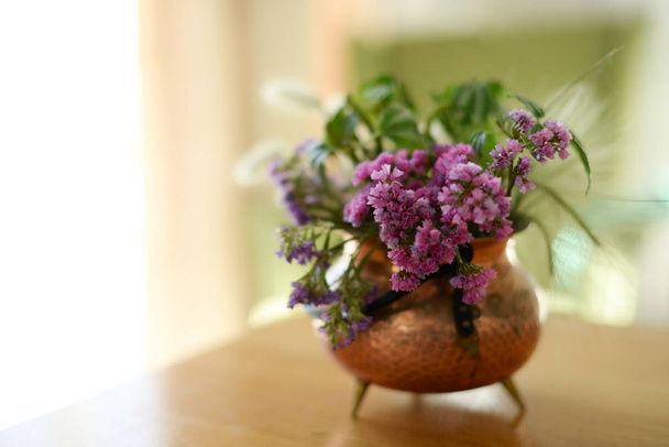 βάζο χαλκού για τέφρα με ένα μπουκέτο από βότανα και αποξηραμένα λουλούδια στο τραπέζι, ακόμα ζωή - Φωτογραφία, εικόνα