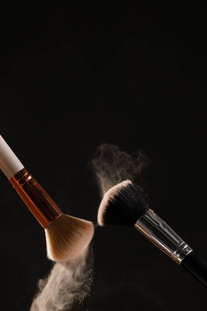 Make up cosmetic brushes with powder blush explosion on black background. Skin care or fashion concept. - Foto, Imagem