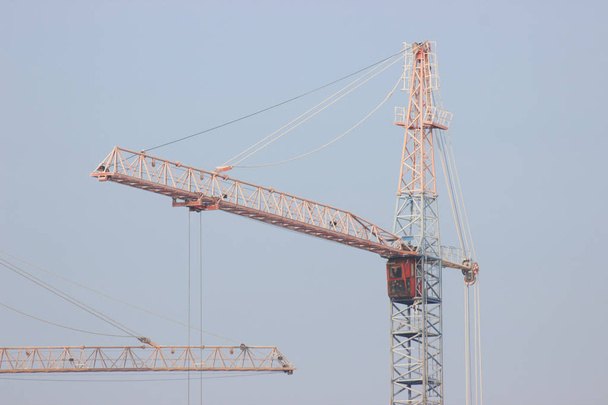 Construction site with yellow crane on blue sky background. Construction, construction work, lifting heavy loads up - Photo, Image