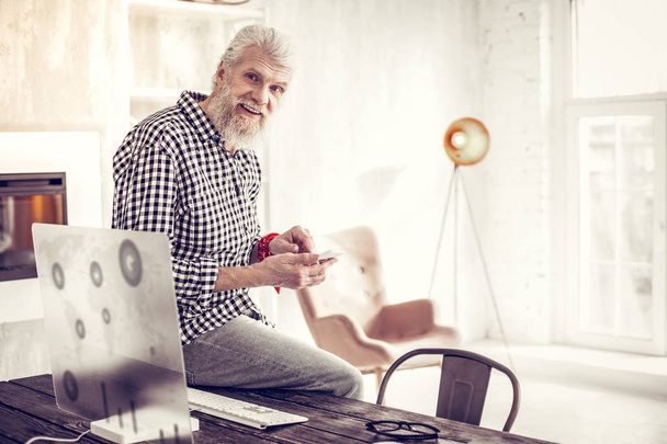 Positive delighted mature male sitting on the table - Photo, image