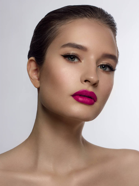 Close-up of the beauty of the female face with a classic evening make-up. Smooth black arrows on the eyelids, long eyelashes and pink lips. Beauty and cosmetology. Clean face skin - Φωτογραφία, εικόνα