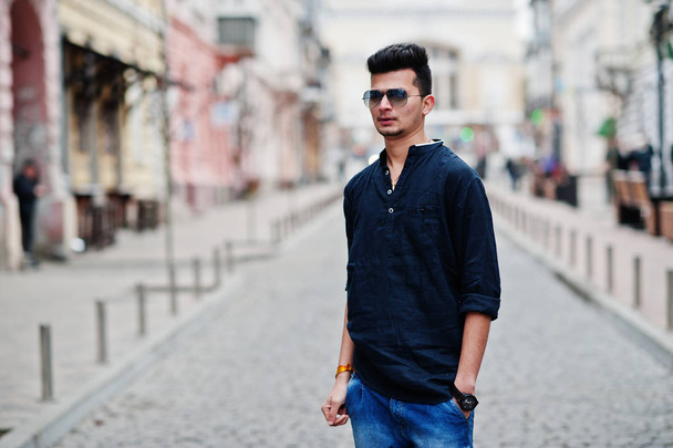Stylish indian model man in casual clothes, black shirt and sunglasses posed outdoor at street of India. - Fotografie, Obrázek