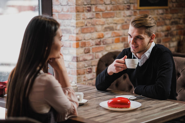 The man looks at the girl, at the cafe table, drinking tea, a loving couple. - Valokuva, kuva