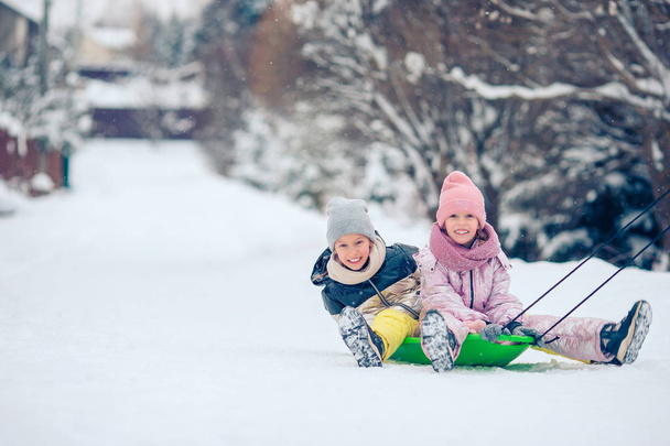 Чарівні маленькі щасливі дівчата катаються в зимовий сніжний день
. - Фото, зображення