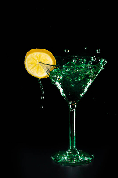 Green cocktail water drink splash in the glass with lemon Isolated on black background - Foto, Imagen