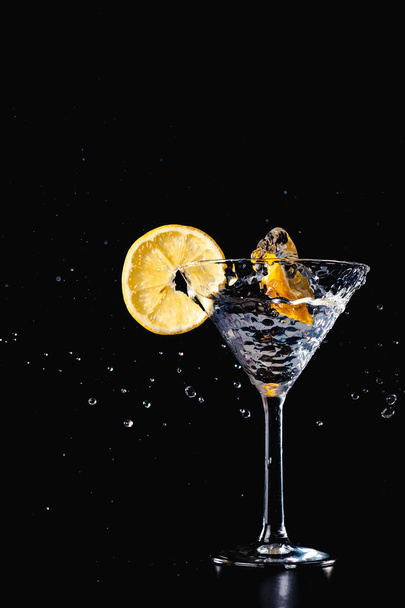 Cocktail bevanda acqua spruzzata nel bicchiere con limone isolato su sfondo nero
 - Foto, immagini