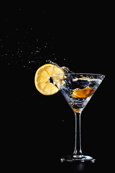 Koktél vizet inni splash a pohár citromos elszigetelt fekete háttér - Fotó, kép