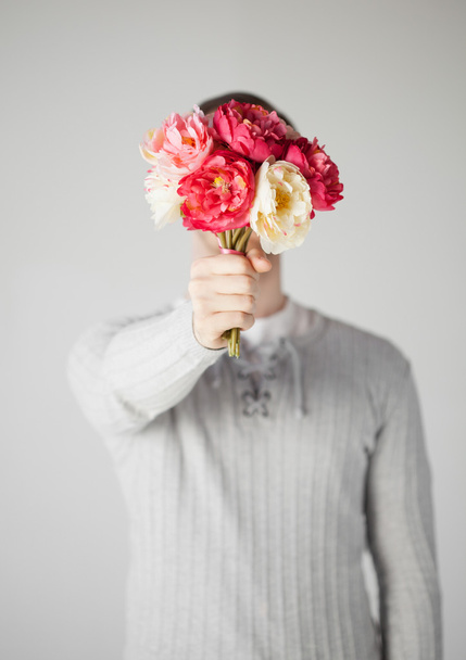 花の花束と彼の顔を覆っている男 - 写真・画像