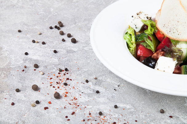 Close up view on Greek salad on a concrete background with spices. Greek cuisine, vegetarian food with free copy space for text, logo. Picture for recipe. Flat lay - Photo, image