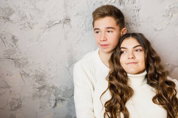 young beautiful couple in white clothes sitting on gray background - Foto, afbeelding