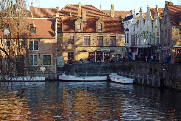 Bruges, Belçika, Aralık 2018. Belçika Bruges Şehir kale kanal, tekneler, köprü ve tuğla duvar güzel manzarasına. Batan güneşin ışınları şehirde. - Fotoğraf, Görsel