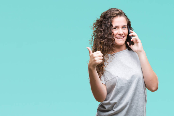 Молода брюнетка дівчина розмовляє на смартфоні над ізольованим тлом щаслива з великою посмішкою роблячи знак ОК, великий палець пальцями, відмінний знак
 - Фото, зображення