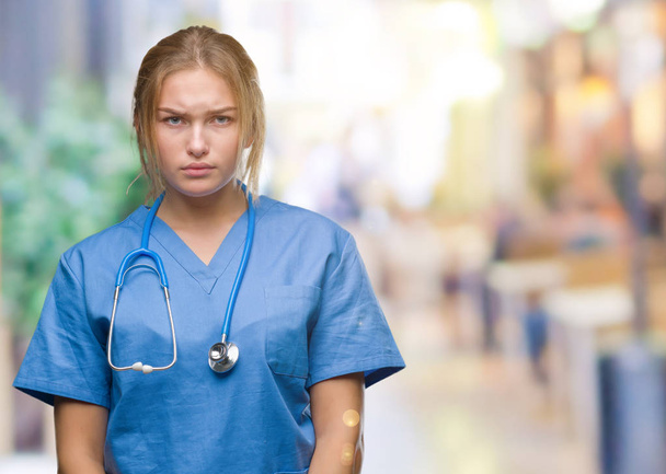 Young caucasian doctor woman wearing surgeon uniform over isolated background skeptic and nervous, frowning upset because of problem. Negative person. - Photo, Image