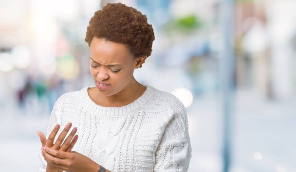 Красива молода жінка афро-американських носити светр над ізольованих фон страждання болю на руки і пальці, артрит запалення - Фото, зображення