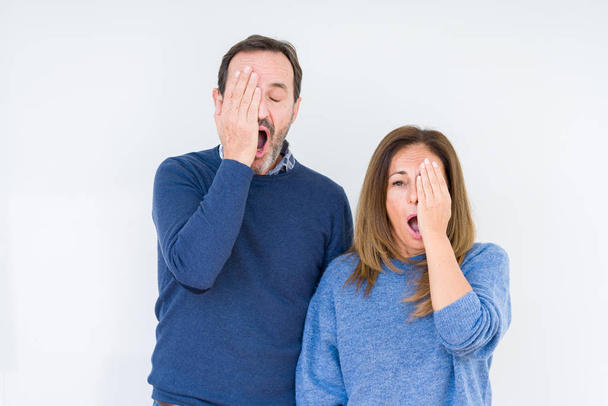 Beautiful middle age couple in love over isolated background Yawning tired covering half face, eye and mouth with hand. Face hurts in pain. - Фото, изображение