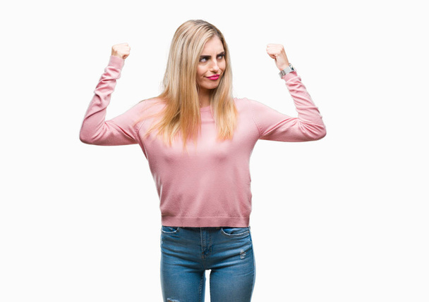 Young beautiful blonde woman wearing pink winter sweater over isolated background showing arms muscles smiling proud. Fitness concept. - Фото, изображение