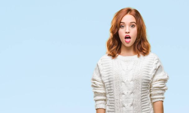 Young beautiful woman over isolated background wearing winter sweater afraid and shocked with surprise expression, fear and excited face. - Foto, Imagen