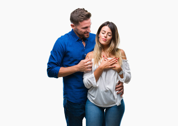 Young couple in love over isolated background smiling with hands on chest with closed eyes and grateful gesture on face. Health concept. - Foto, afbeelding