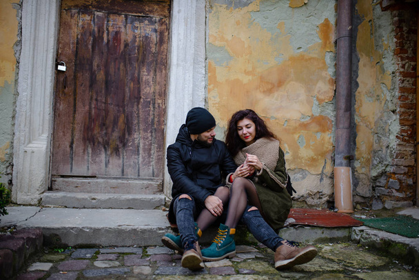 Una joven pareja romántica que viste ropa de abrigo al aire libre en Navidad, sentada en un banco en la calle de la noche decorada con hermosas luces
. - Foto, imagen