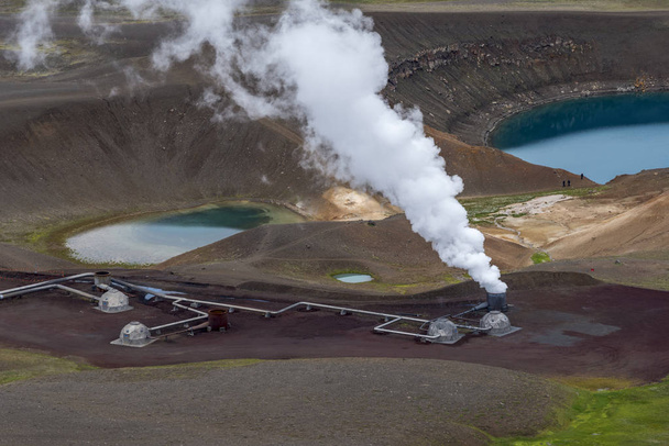 Zobacz na aktywnej parze stos i części elektrowni geotermalnej Krafla obok krateru wulkanu z jeziorem Kravla Viti w regionie Nordurland eystra Północnej Islandii.   - Zdjęcie, obraz
