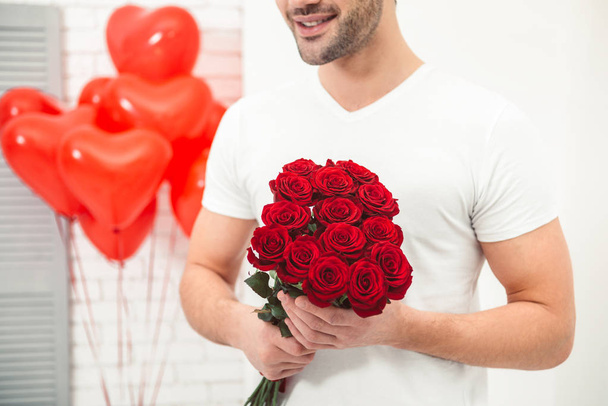 portrait of smiling man holding bouquet of red roses, valentines day concept - Foto, Bild