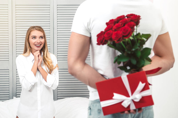 happy young woman waiting for the gifts from boyfriend holding them behind his back - Photo, Image