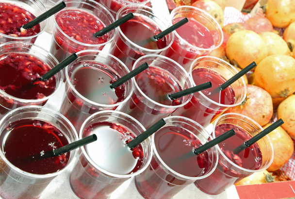 πολλά πλαστικά ποτήρια με χυμό φρούτων από βιολογικό ρόδι προς πώληση - Φωτογραφία, εικόνα