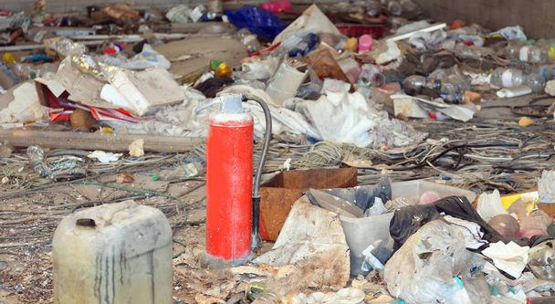 dakloze schuilplaats met veel vuilnis en een rode brak verlaten blusser - Foto, afbeelding