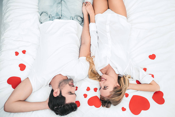 幸せなカップルは、ベッドで手をつないで、お互いを見て、バレンタインデーの概念 - 写真・画像