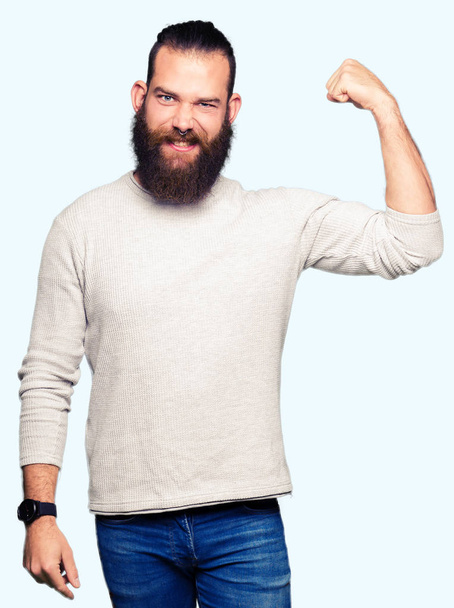 junger blonder Mann trägt lässigen Pullover starke Person zeigt Armmuskeln, selbstbewusst und stolz auf die Macht - Foto, Bild