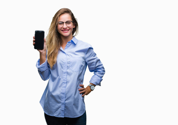 Joven mujer de negocios rubia hermosa mostrando la pantalla del teléfono inteligente sobre un fondo aislado con una cara feliz de pie y sonriendo con una sonrisa segura que muestra los dientes
 - Foto, Imagen