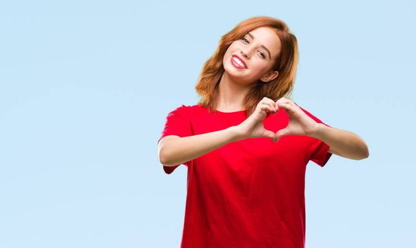 Young beautiful woman over isolated background smiling in love showing heart symbol and shape with hands. Romantic concept. - Фото, зображення