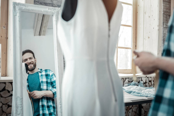 Man smiling while looking into mirror after designing dress - Фото, зображення