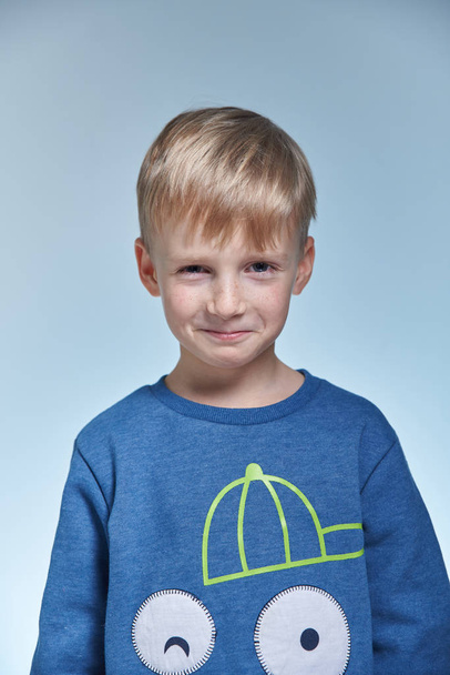 портрет смешного эмоционального и хитрого мальчика в студии 7 лет, с суженными глазами
 - Фото, изображение