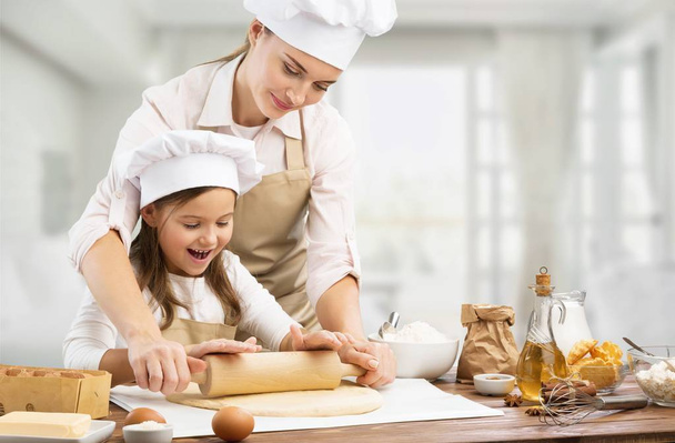 Portrait of adorable little girl and her mother baking together  - Zdjęcie, obraz