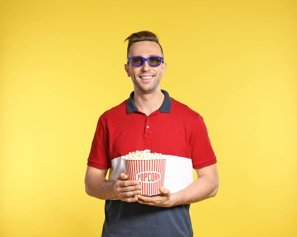 Man with 3D glasses and popcorn during cinema show on color background - Fotografie, Obrázek