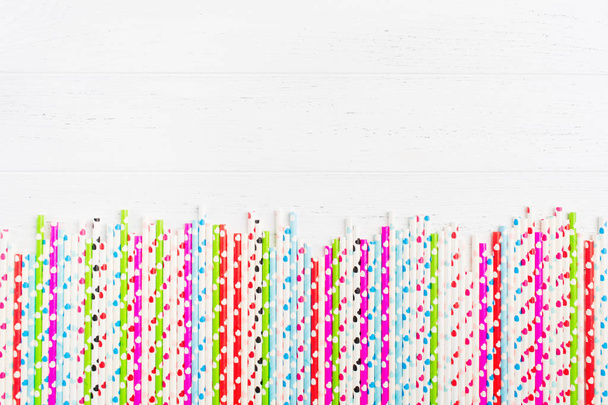 Colorful ecological plastic free paper straw with hearts on white wooden background with copy space - Foto, Imagem