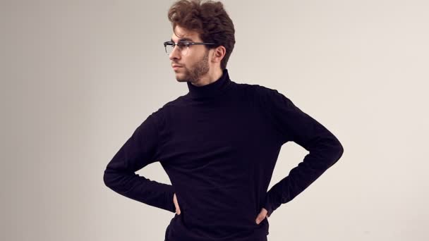 Portrait de mode d'un bel homme élégant aux cheveux bouclés portant col roulé noir et lunettes sur fond gris en studio
 - Séquence, vidéo