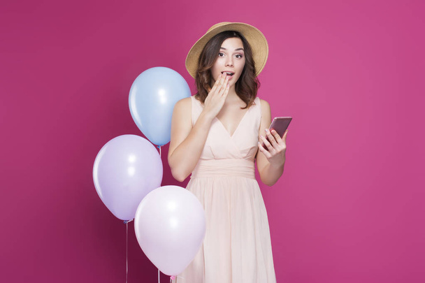 chica sorprendida con un teléfono en sus manos sobre un fondo rosa
 - Foto, Imagen