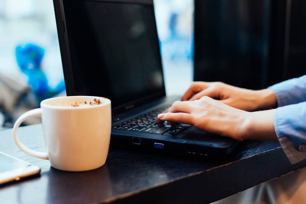on a wooden table is a laptop and a cup of coffee - 写真・画像
