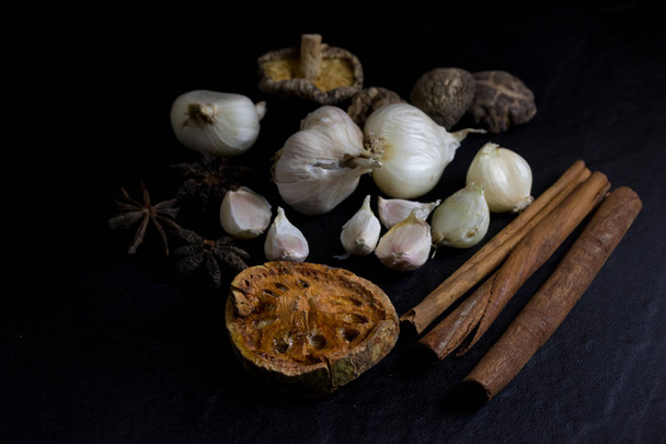 Garlic and dry bael fruit tea and Mushroom, cinnamon, Star anise isolated on black background - Foto, imagen