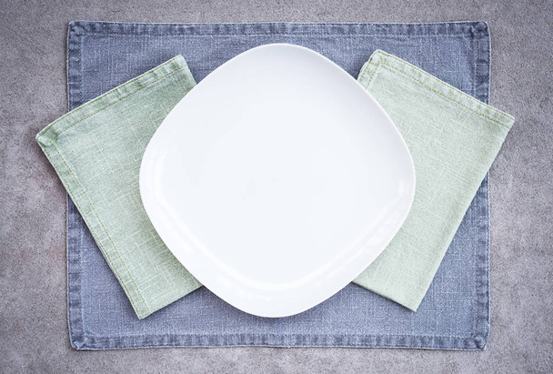 Assiette blanche et textiles simples en lin sur fond béton. Couleurs pastel
. - Photo, image