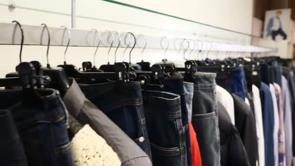 Shooting clothes for woman and man. hangers for clothing in store indoors. Close up Shot clothing in score, long line with black rack with dresses, skirts, coats, sweaters, jackets, pants, blouses - Footage, Video