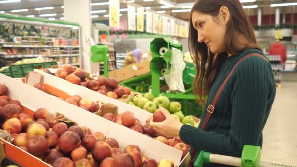 Attractive young woman choosing apple at fruit vegetable supermarket marketplace - Séquence, vidéo