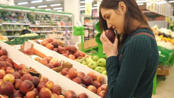 mujer joven eligiendo manzana roja en el supermercado de frutas y verduras
 - Metraje, vídeo
