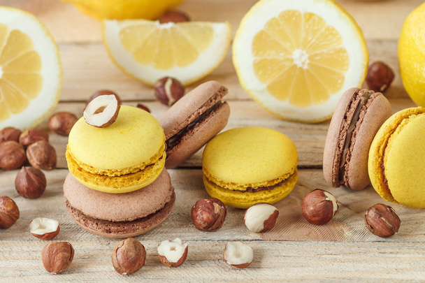 Yellow and brown french macarons with lemon and hazelnuts, soft focus background - 写真・画像