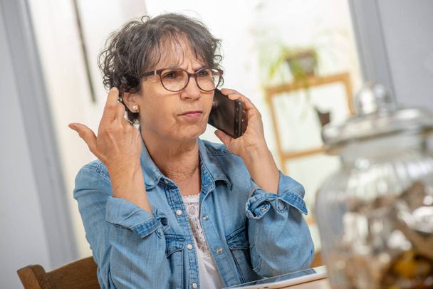 una mujer de mediana edad feliz con gafas usando y hablando de teléfono
  - Foto, Imagen