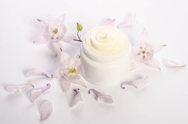 Cute flowers and petals and a jar of natural body cream isolated on white background - Photo, image