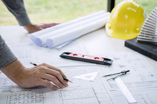 Bauingenieur- oder Architektenhände arbeiten an der Bauplan-Inspektion am Arbeitsplatz, während sie Informationszeichnungen und Skizzen für die Arbeit an Architekturprojekten prüfen. - Foto, Bild