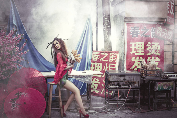 Um modelo sexy escassamente vestido posa com varas de massa frita em uma barraca de comida em uma rua na cidade de Weifang, província de Shandong, leste da China, 4 de março de 2016
 - Foto, Imagem